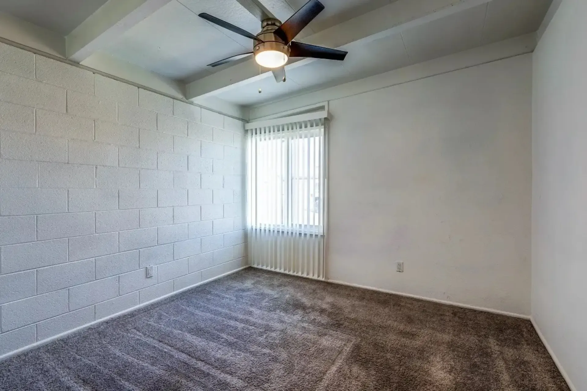 an empty bedroom with a ceiling fan and a window