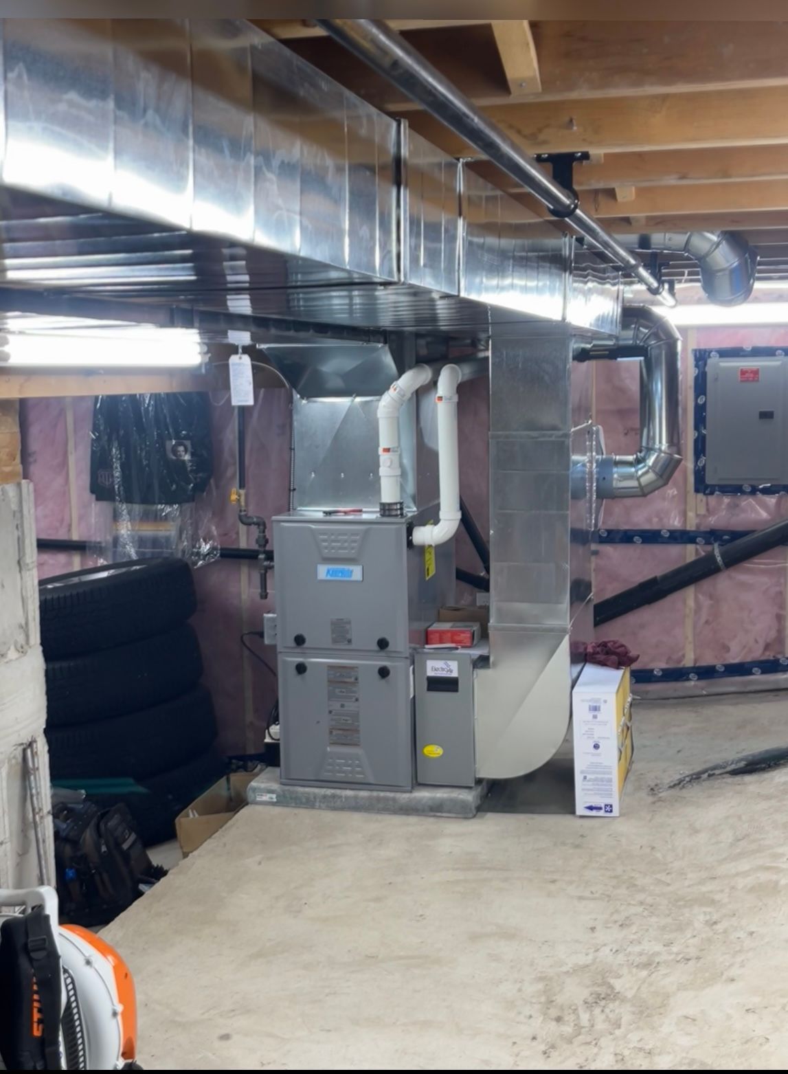 A basement with a furnace and pipes coming out of it