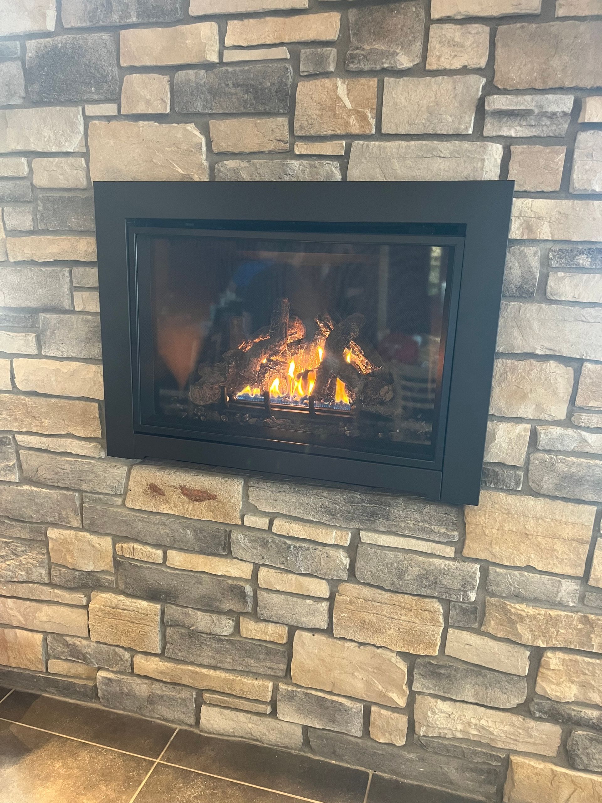 A fireplace is built into a stone wall in a living room.