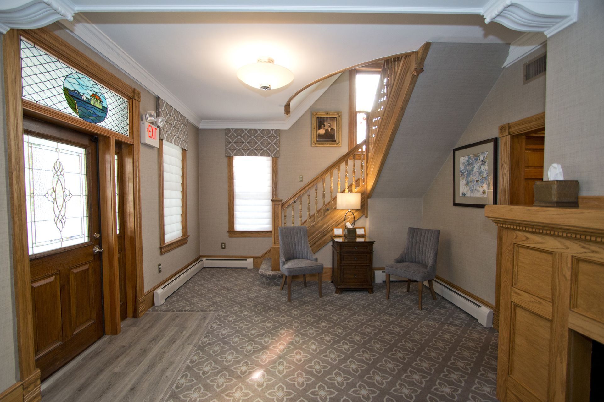 Front entryway with wooden door, staircase, window seat, and patterned carpet in a beige home interior