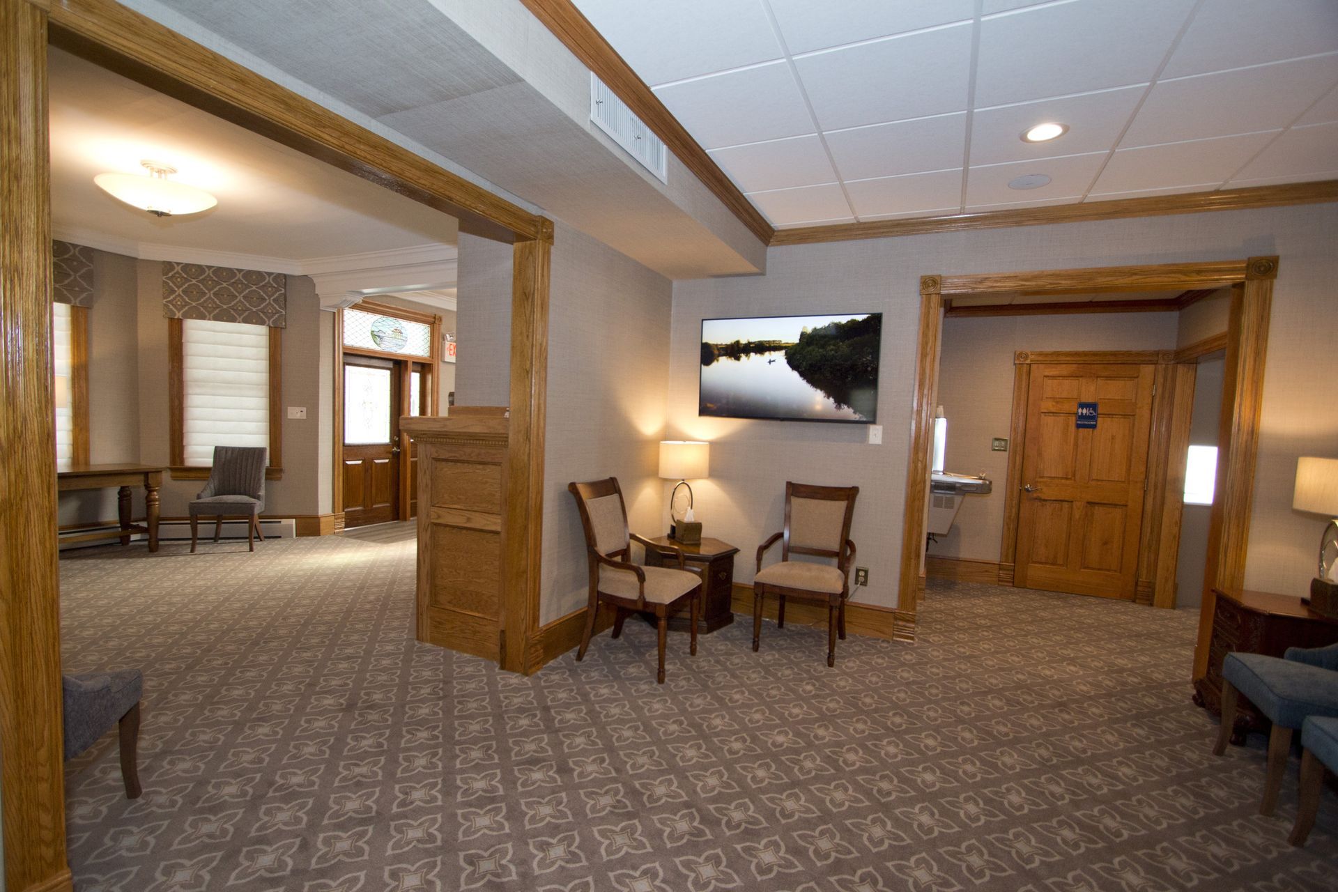 Spacious waiting room with carpet, wooden trim, chairs, and a door in the background