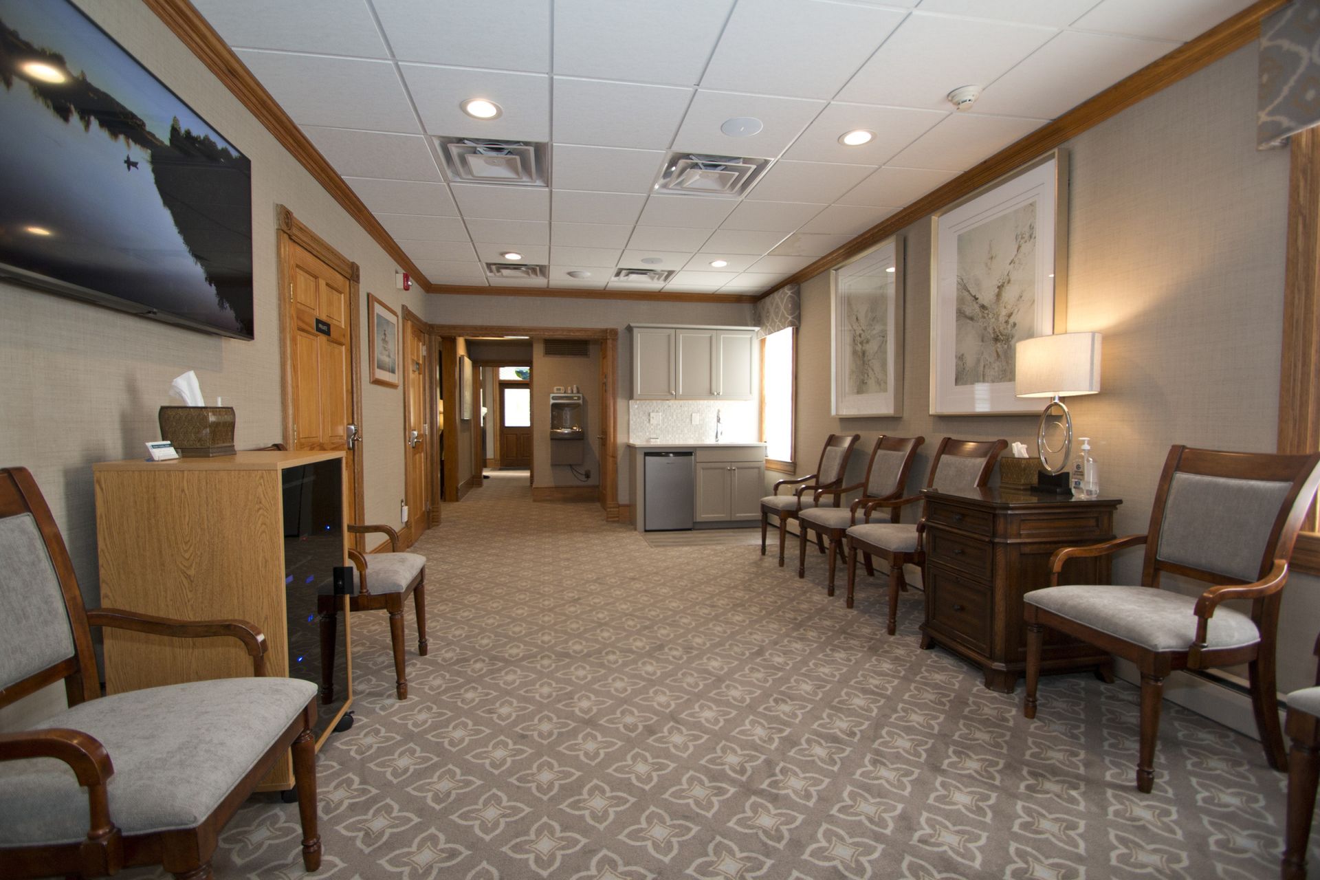 Quiet waiting room with patterned carpet, chairs along the walls, and soft overhead lighting.