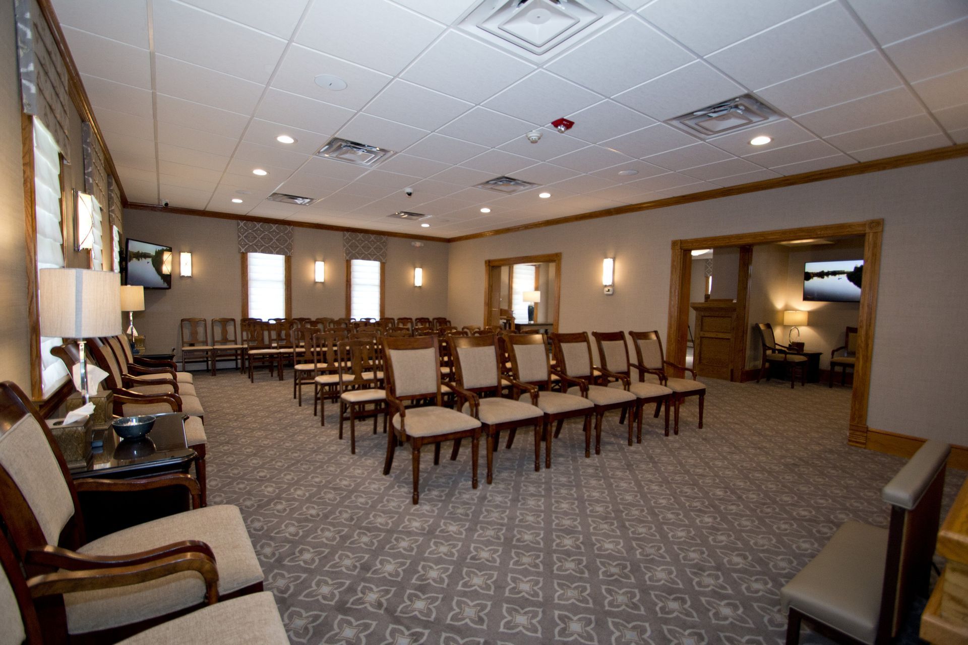 Empty waiting room with rows of brown chairs, patterned carpet, and warm wall sconces in a large conference space
