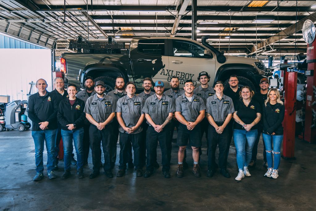 Group of mechanics in a garage, posing in front of a modified truck.