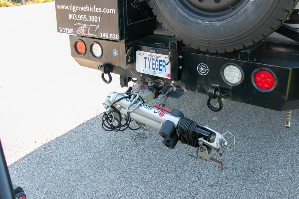 Black truck bumper with trailer hitch and spare tire. License plate