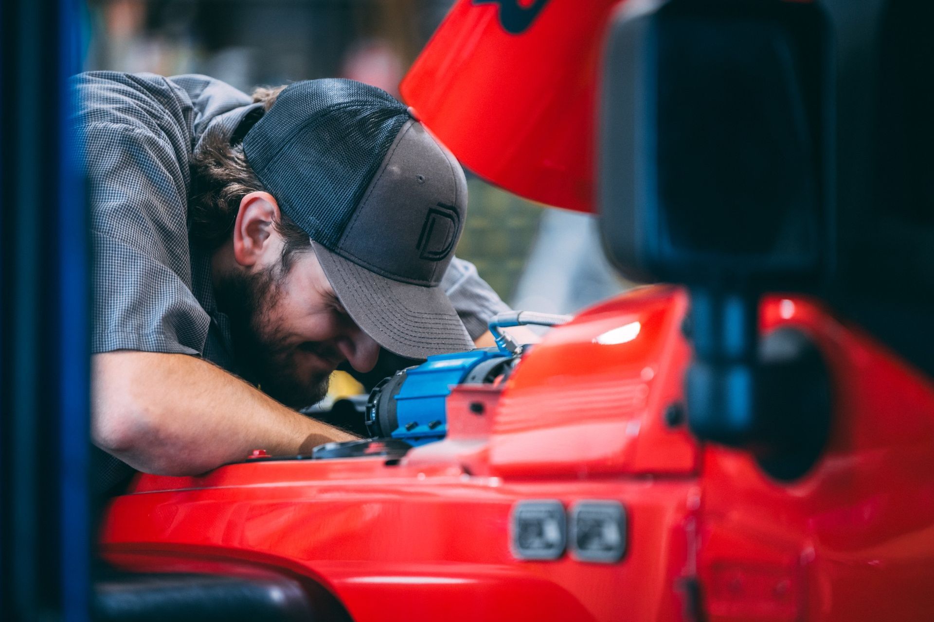Close-up of a technician wearing a dark cap and light blue/gray shirt working intently