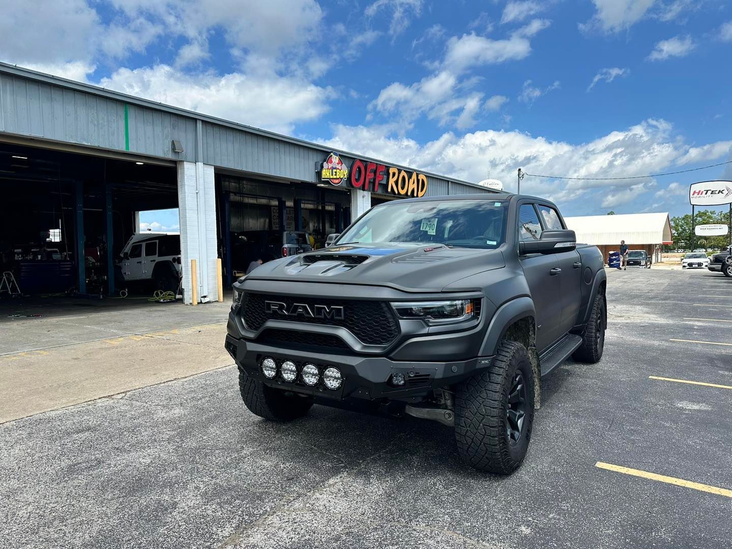 Dark gray Ram TRX pickup truck in front of an auto repair shop with an