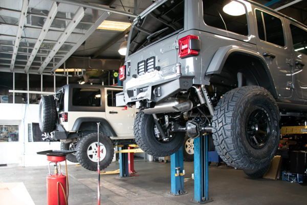 Gray four-wheel-drive vehicle positioned on a red hydraulic two-post lift system