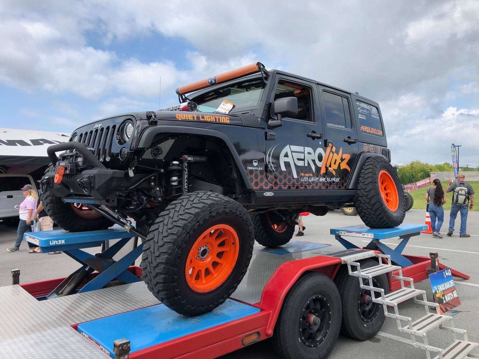 Black Jeep with orange accents on a trailer;