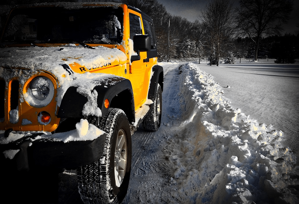 Bright yellow and orange compact off-road vehicle parked on a snowy roadside