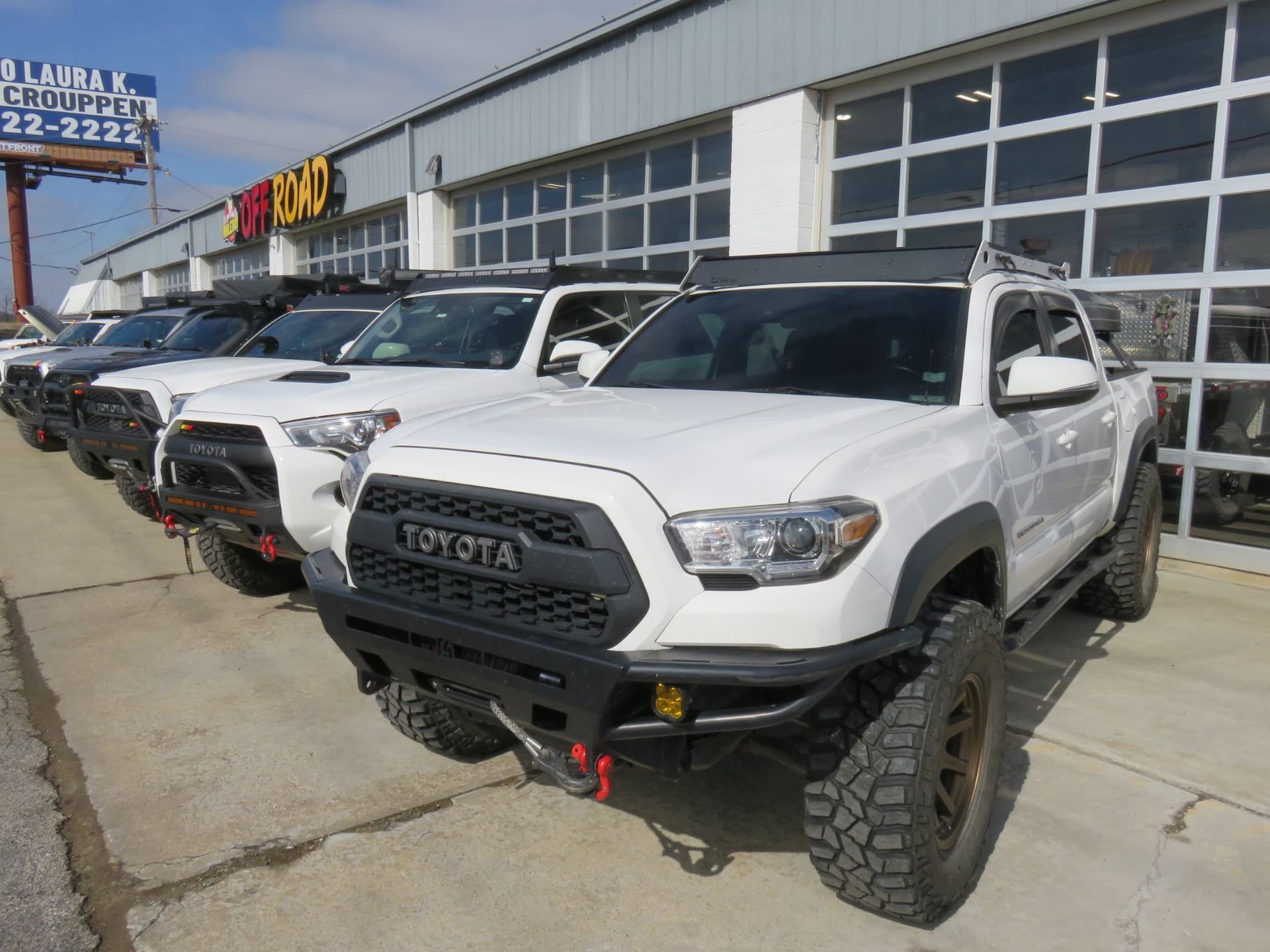 White and black Toyota trucks parked outside a dealership.