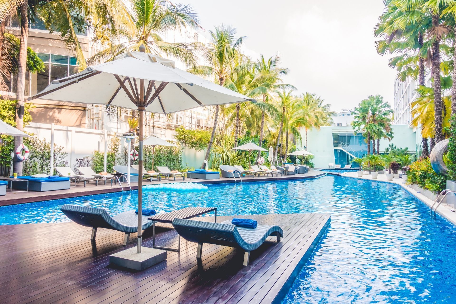 A large swimming pool surrounded by chairs and umbrellas.