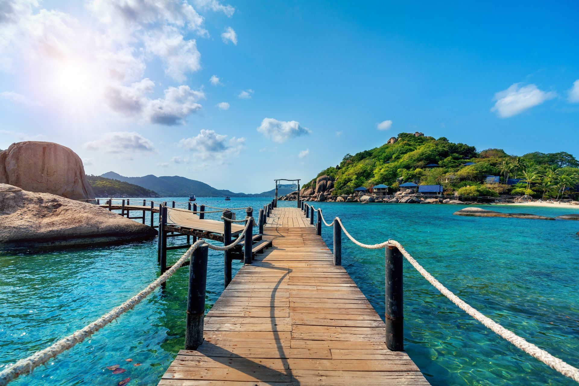 A wooden pier leading to a small island in the middle of the ocean.