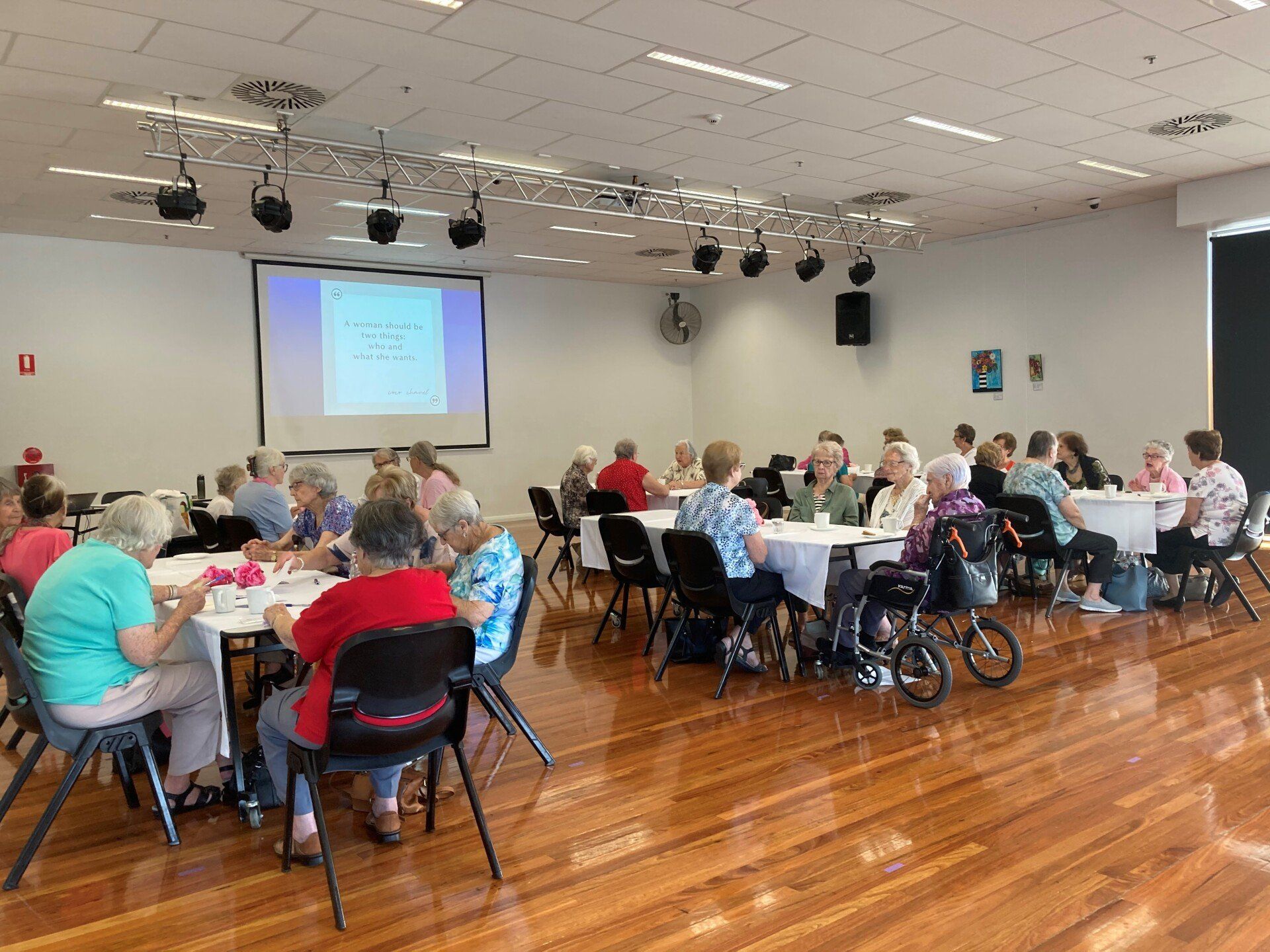 large hall with senior women sitting at tables together talking