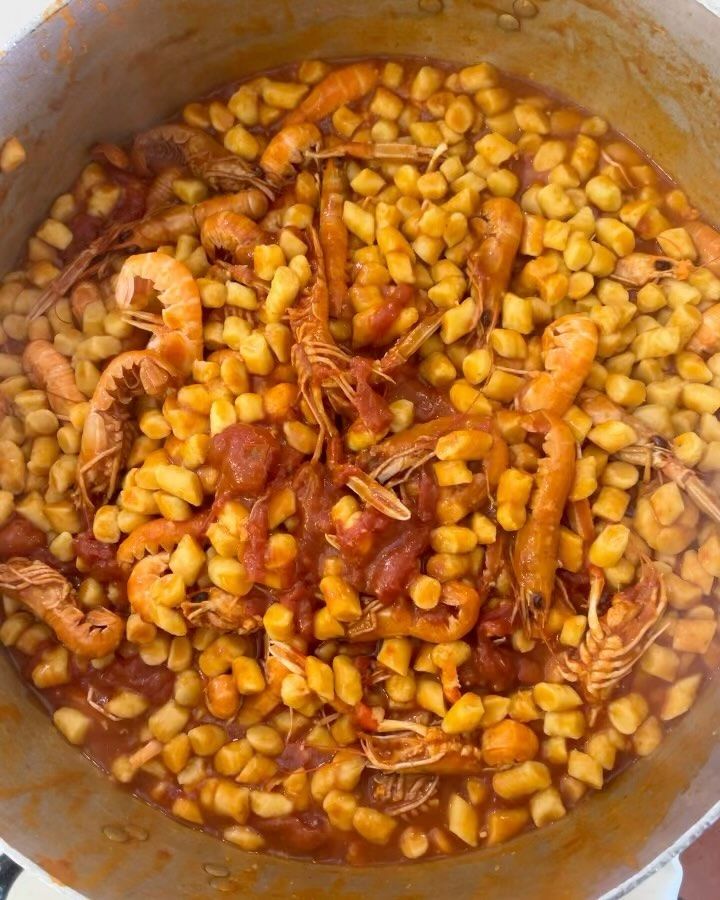 Pentola di gnocchi con gamberi in salsa di pomodoro rosso.