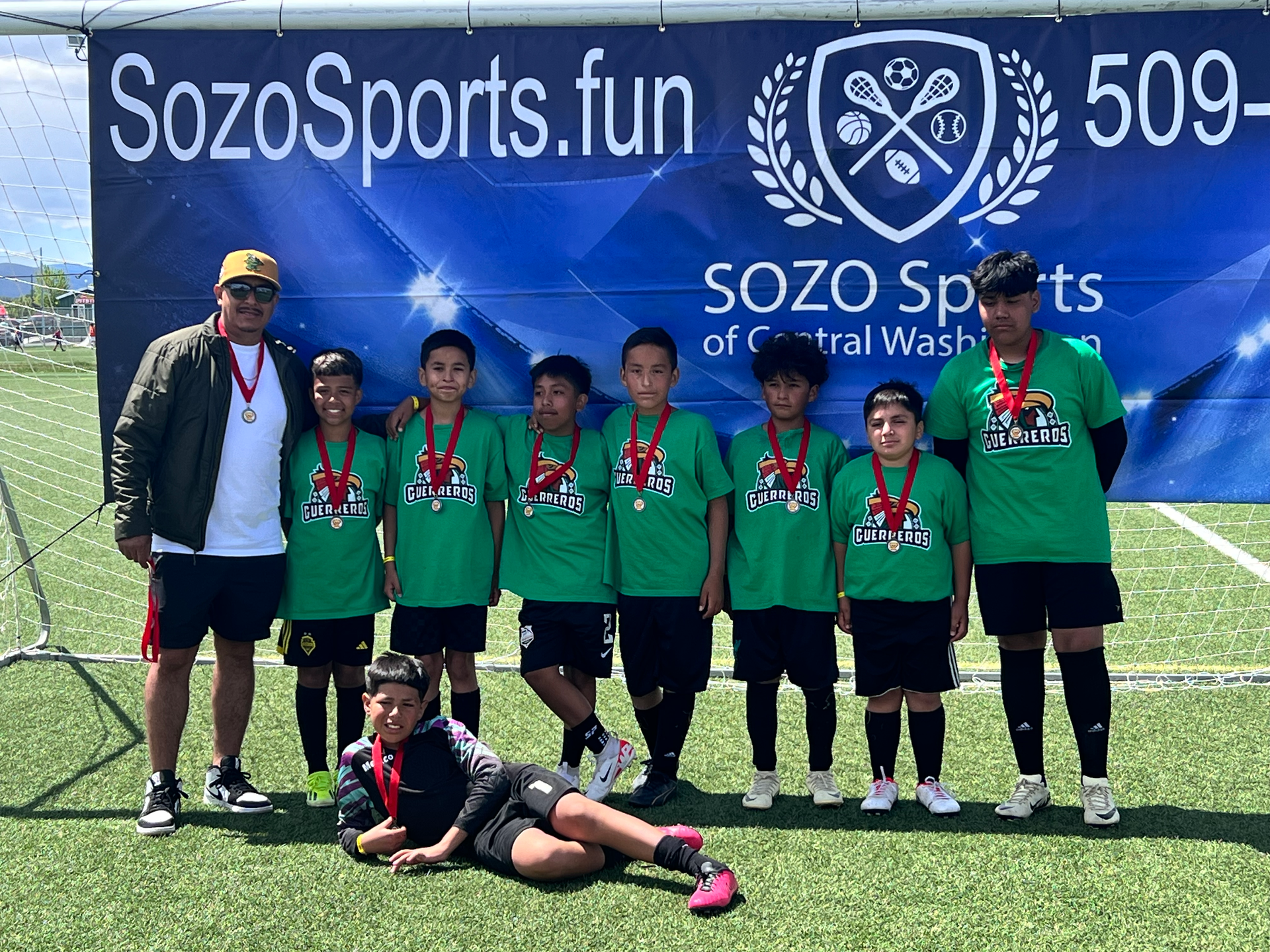A group of boys are posing for a picture on a soccer field.