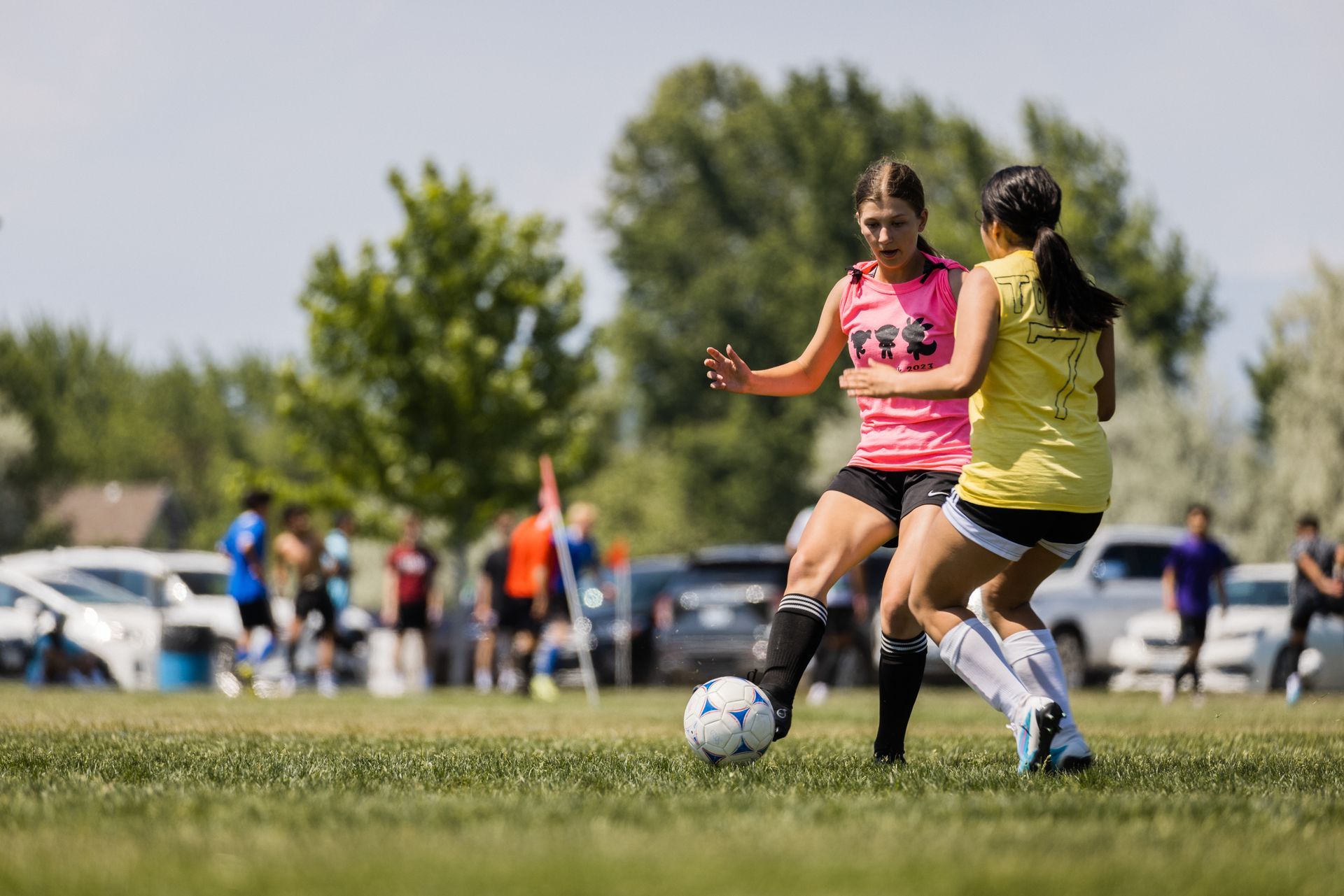 Two girls are playing soccer on a field.