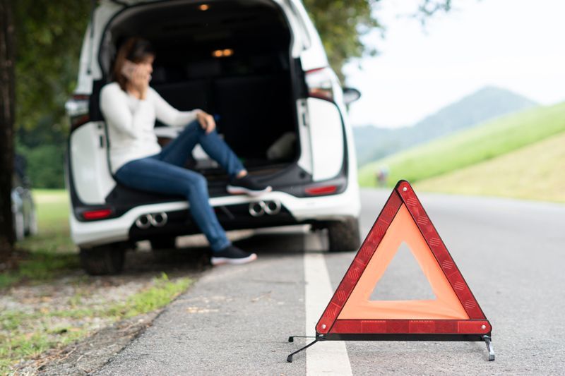 A woman is calling emergency services to help her with a broken car. A woman is calling emergency services to help her with a broken car.