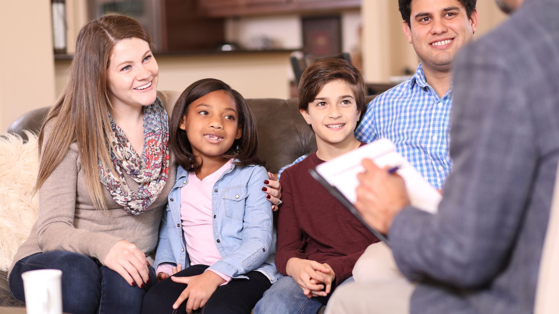 Family seated on a couch listening to a counselor during a therapy session