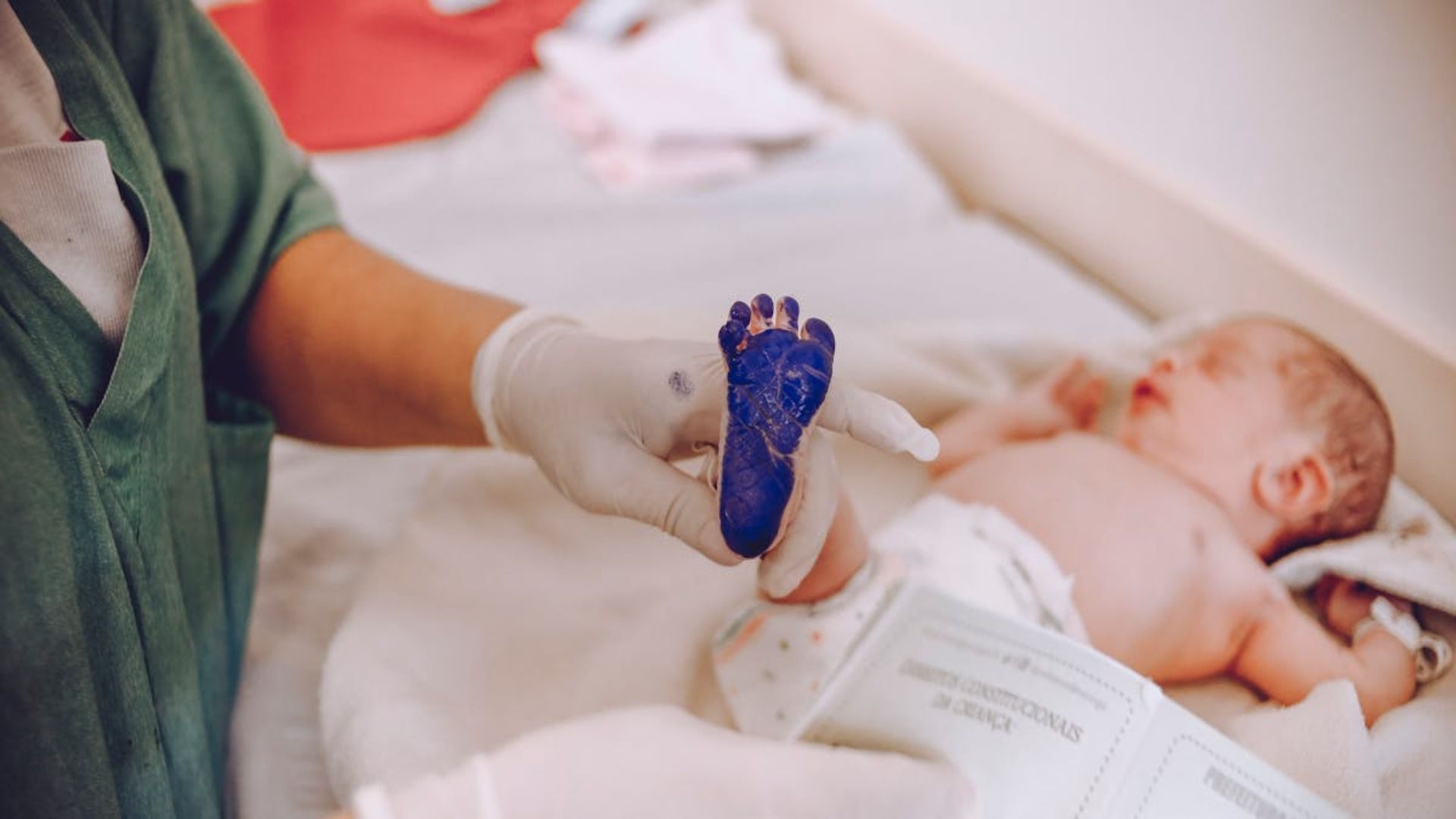 Una enfermera sostiene una huella azul del pie de un bebé.