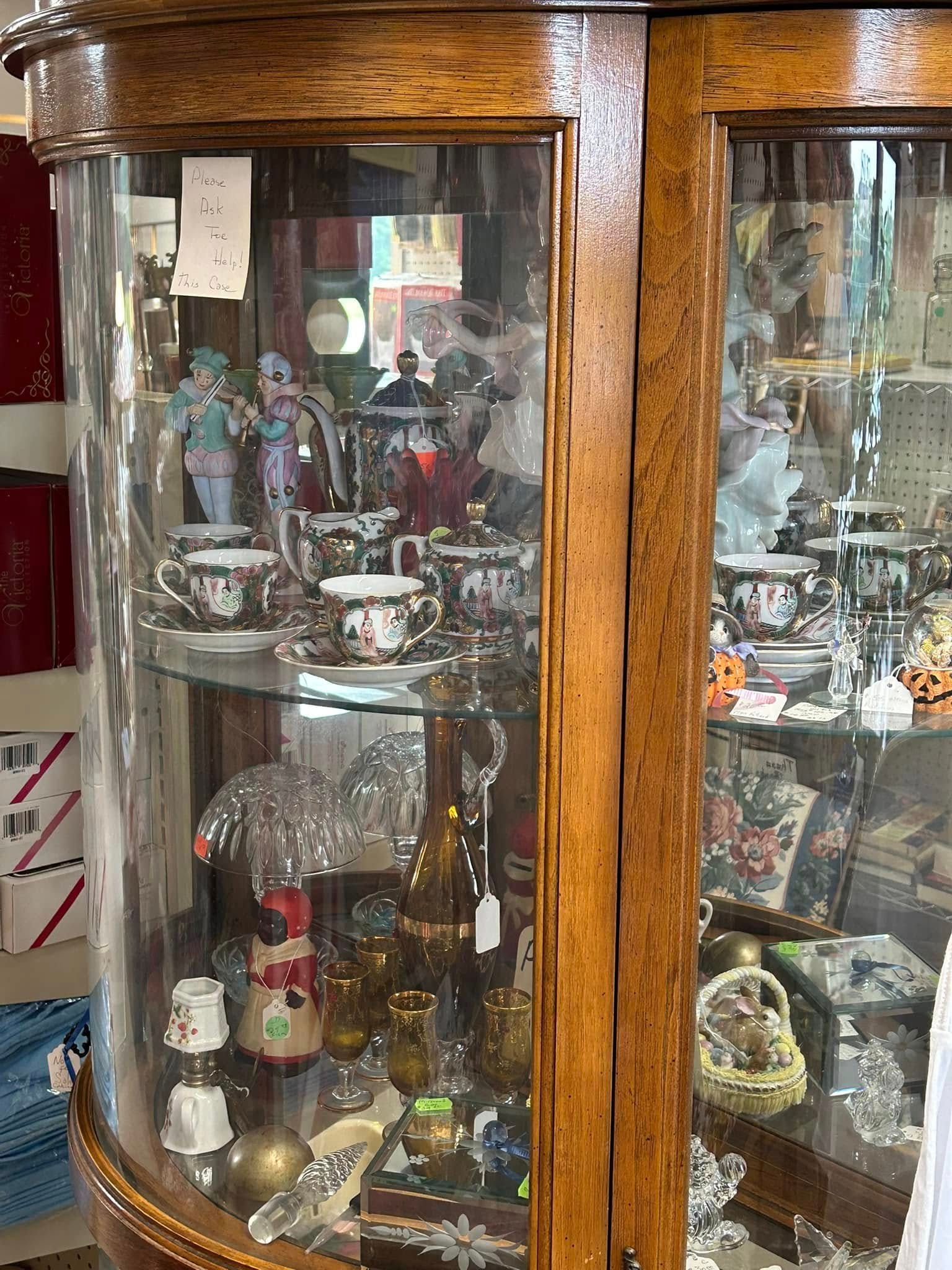 Wooden glass display cabinet filled with assorted decorative figurines and collectibles.