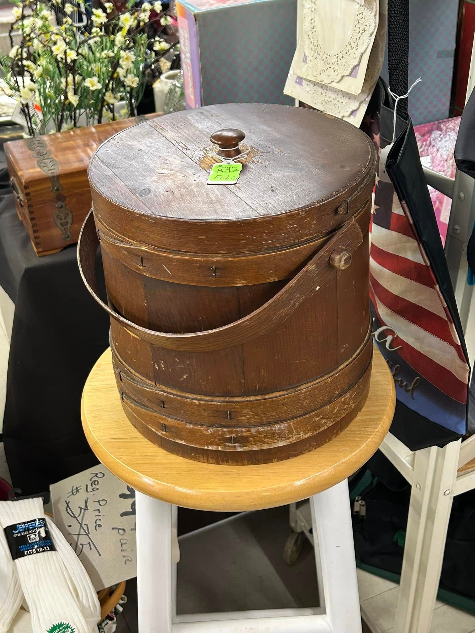 Vintage brown wooden round box on a yellow stool in a shop display