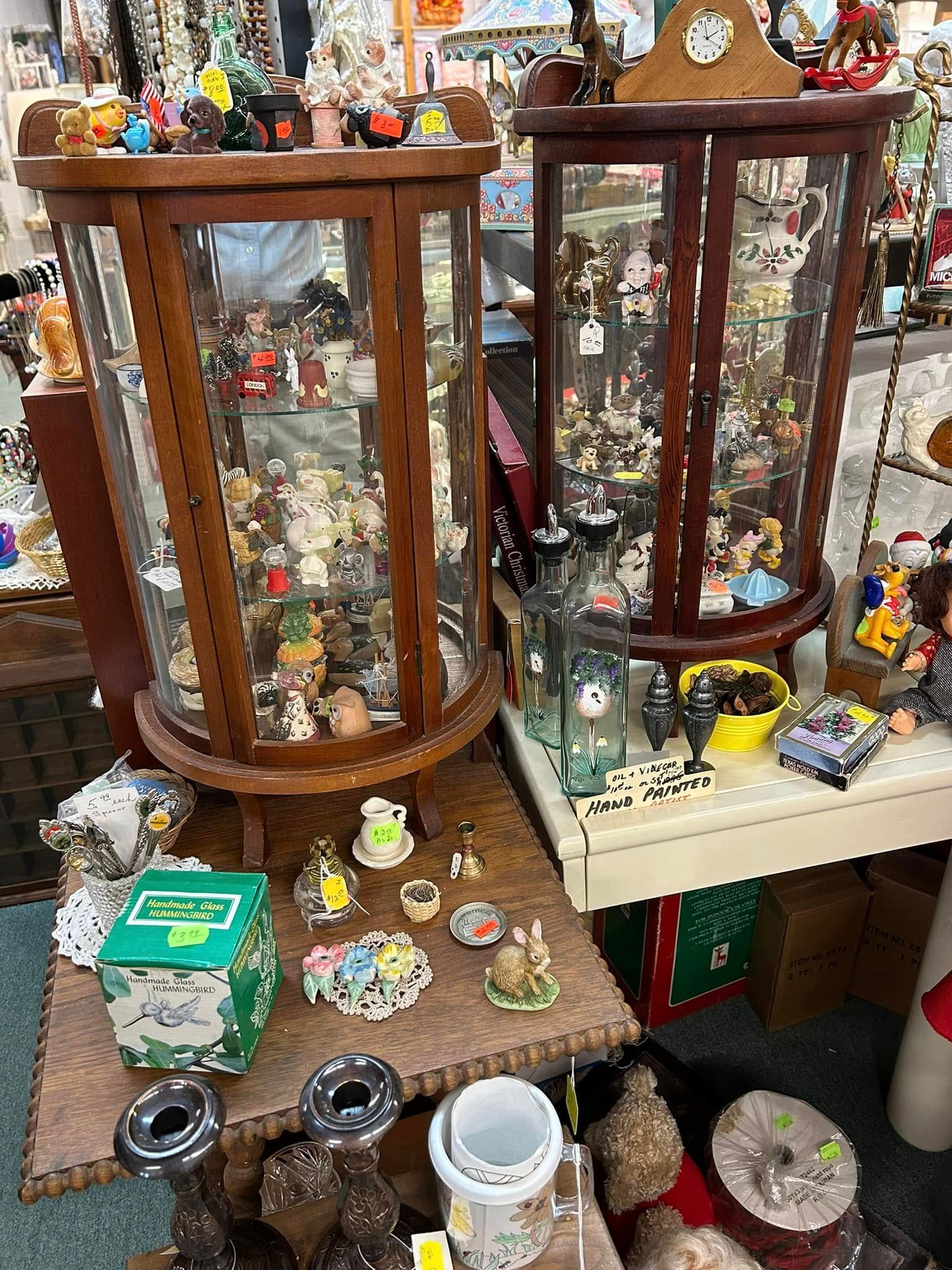 Glass display cabinets filled with trinkets and collectibles in a cluttered shop or market stall