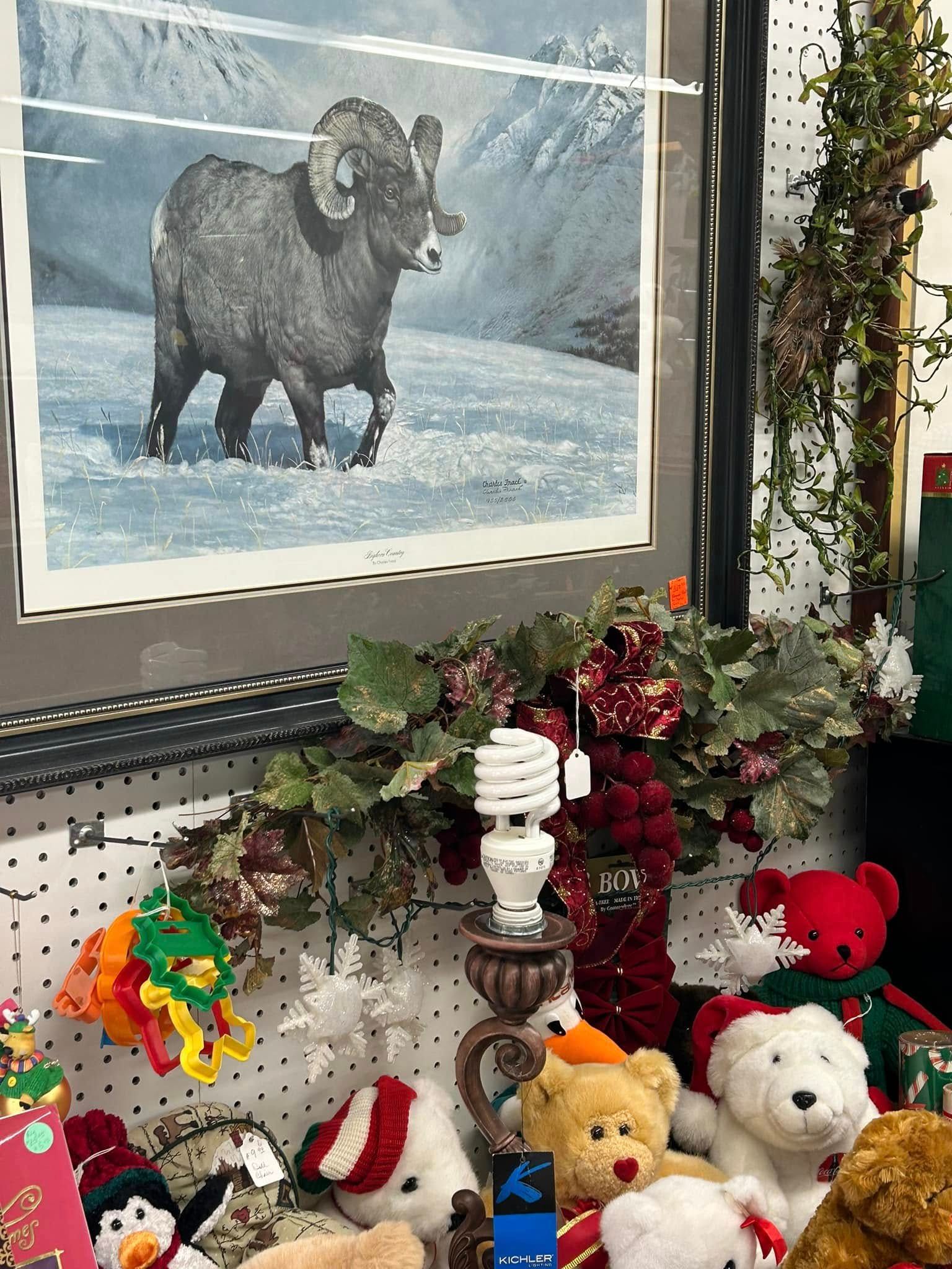 Holiday display with a framed bighorn sheep print, garland, and stuffed animals on a shelf