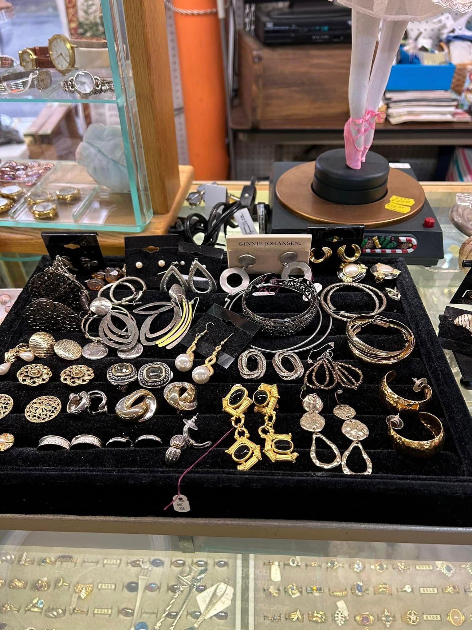 Display of assorted silver, gold, and black bracelets and rings on a black velvet tray in a jewelry shop.
