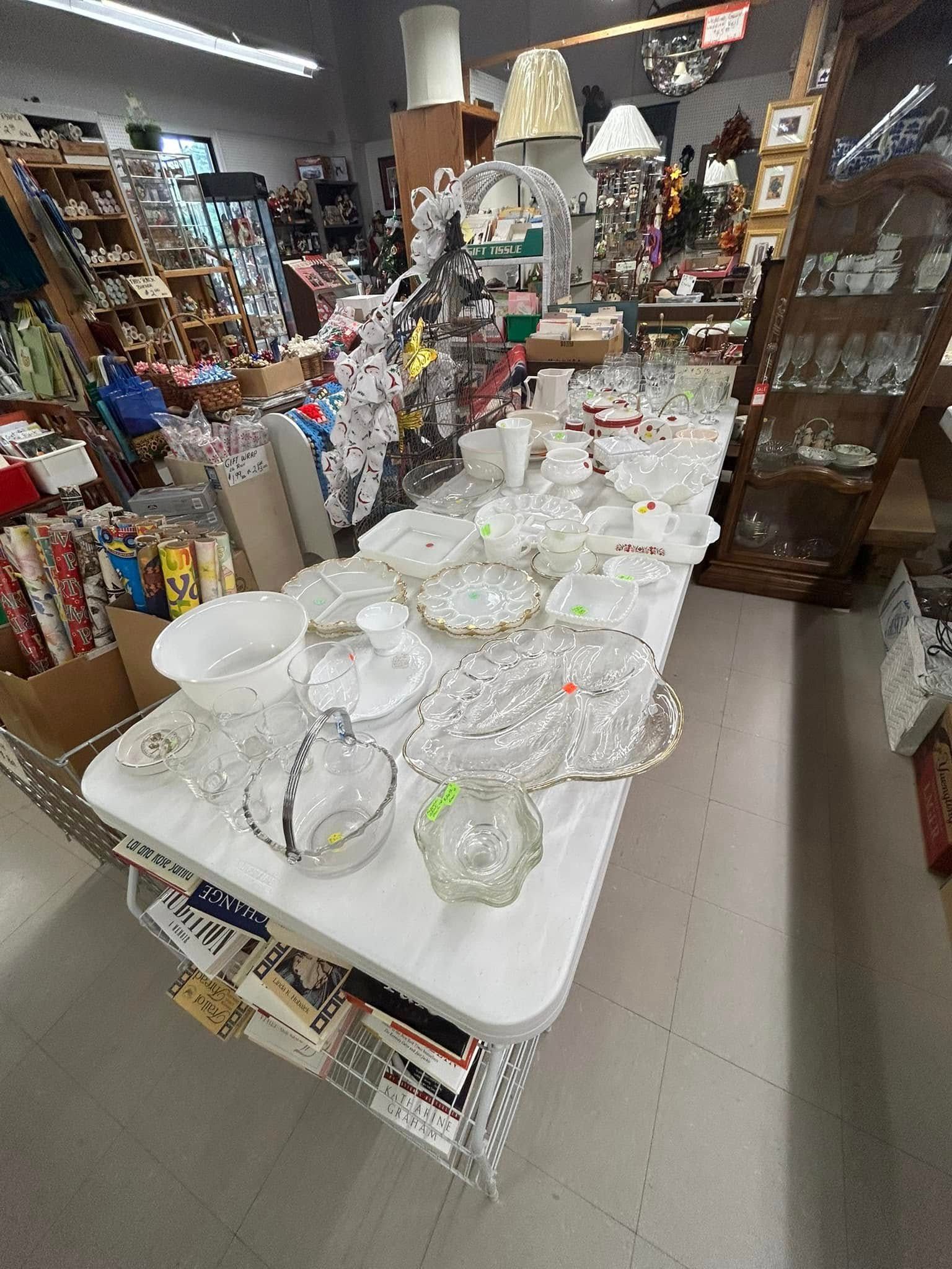 Glassware displayed on a white table in a crowded shop aisle