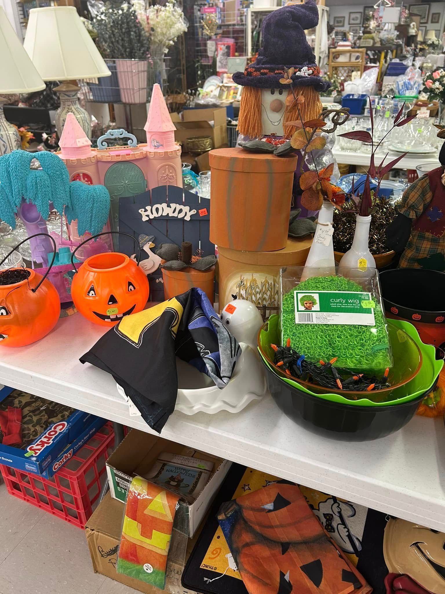 Halloween decorations on a store shelf, including pumpkin buckets, ghosts, bats, and a witch cauldron.