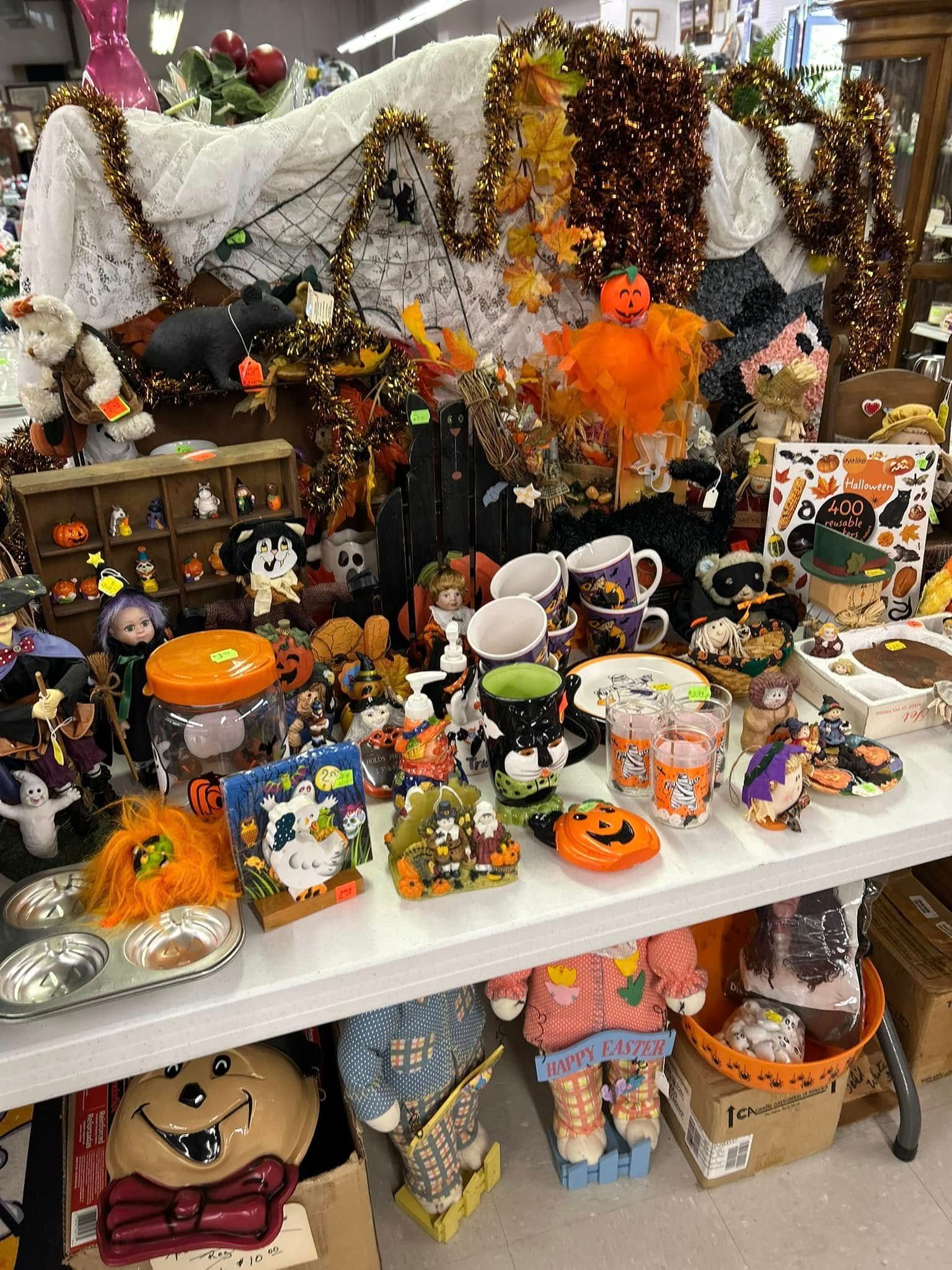 Halloween craft display with spooky decorations, pumpkins, and colorful trinkets on a white shelf
