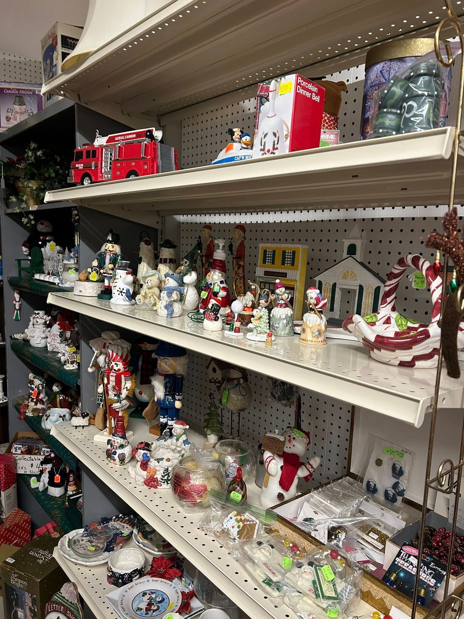Shelves in a store aisle filled with Christmas figurines, ornaments, and holiday decorations.