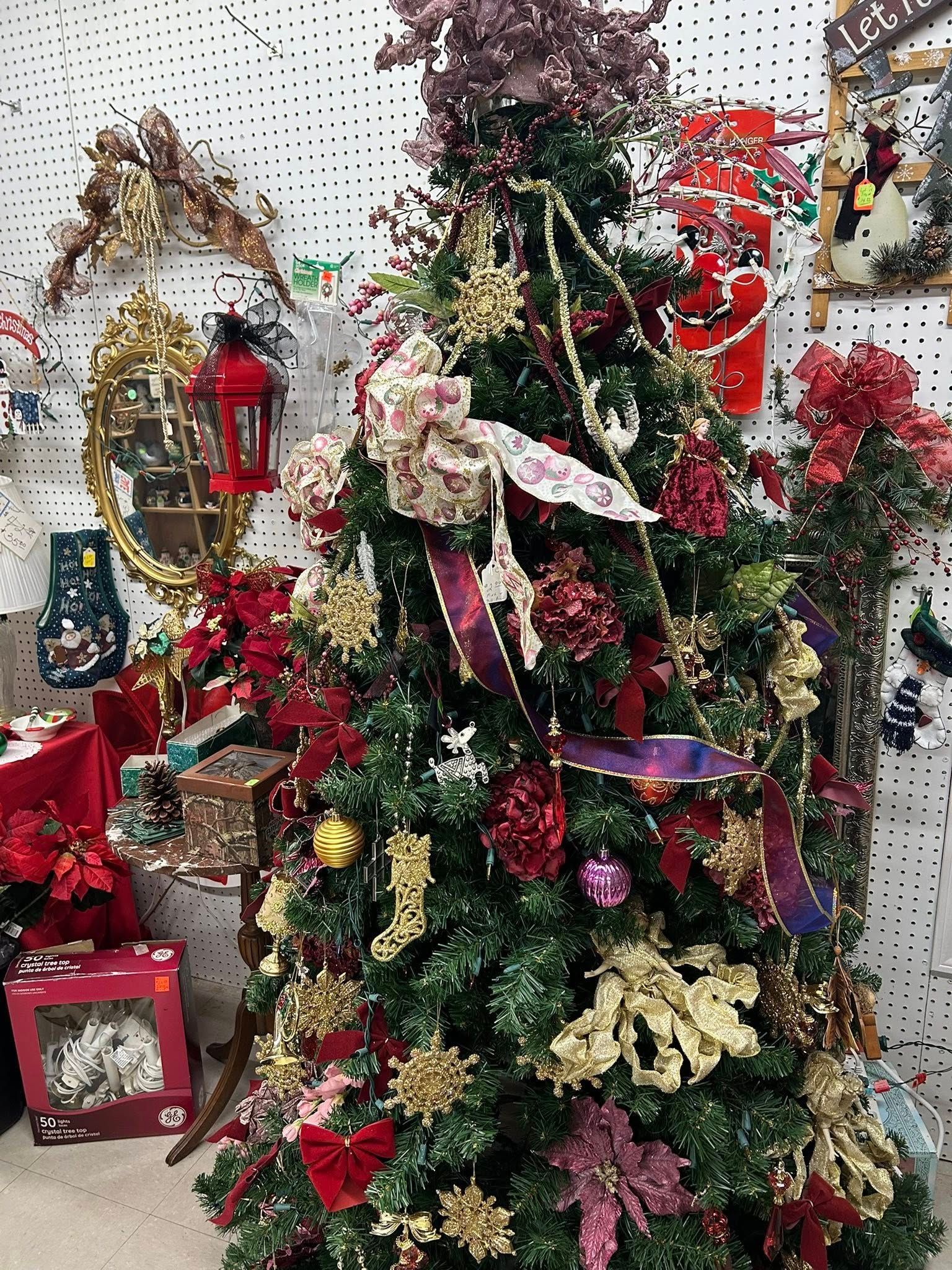 Decorated Christmas tree with red, gold, and white ornaments, bows, and lights in a festive indoor setting
