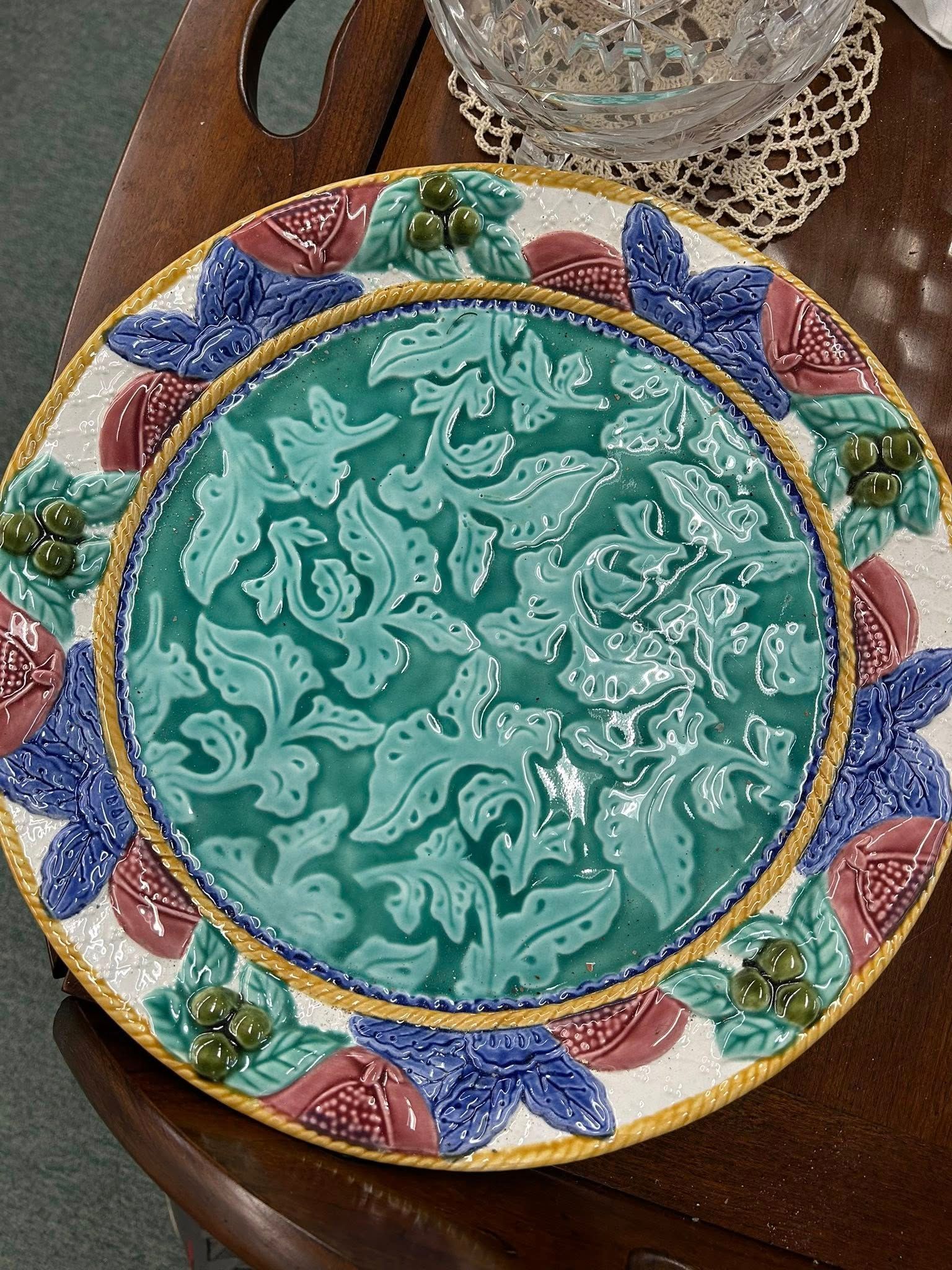 Decorative ceramic plate with teal center and multicolored floral rim on a wooden table
