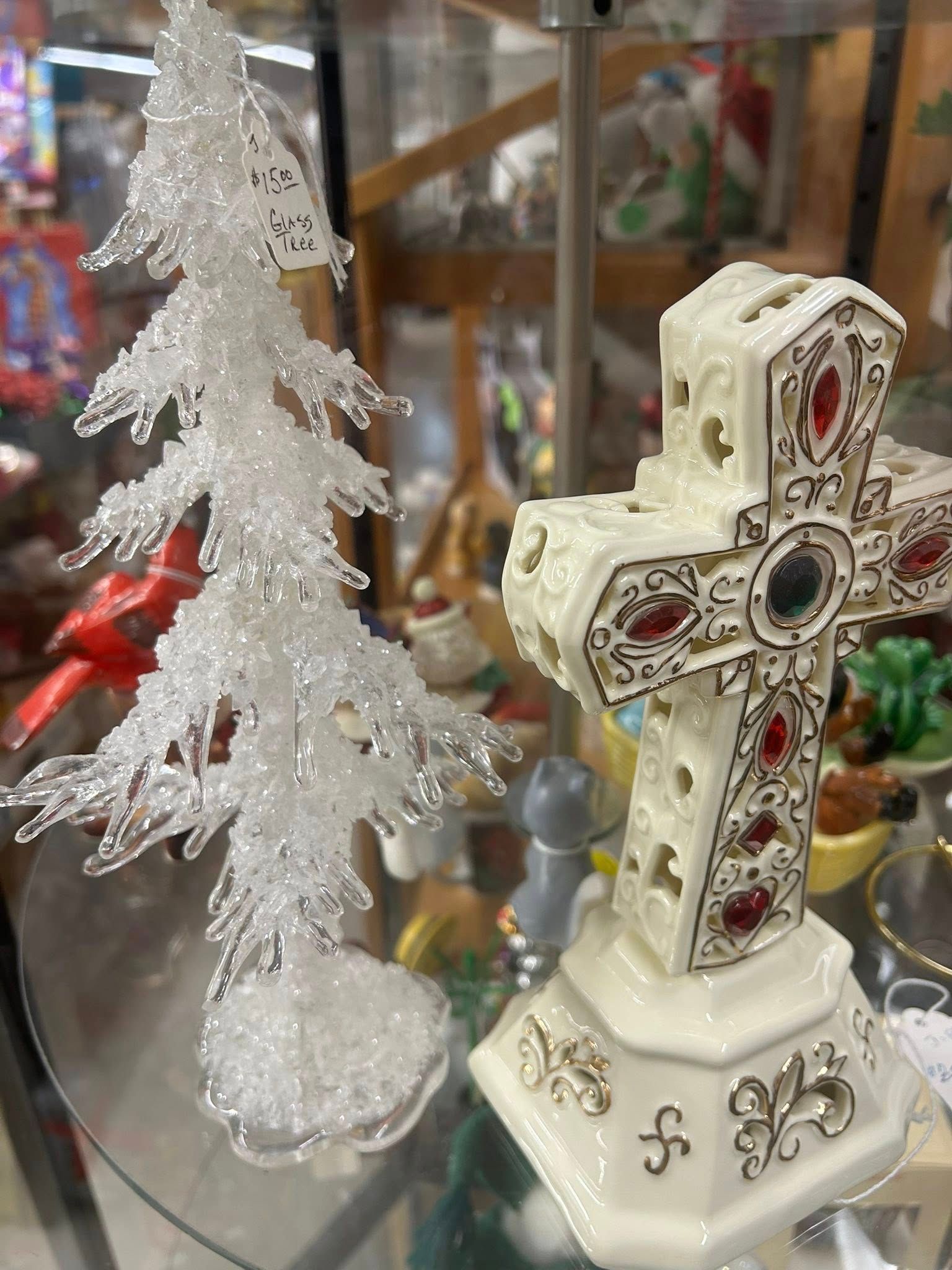 White glittery tree and ornate white cross ornament displayed on a shelf