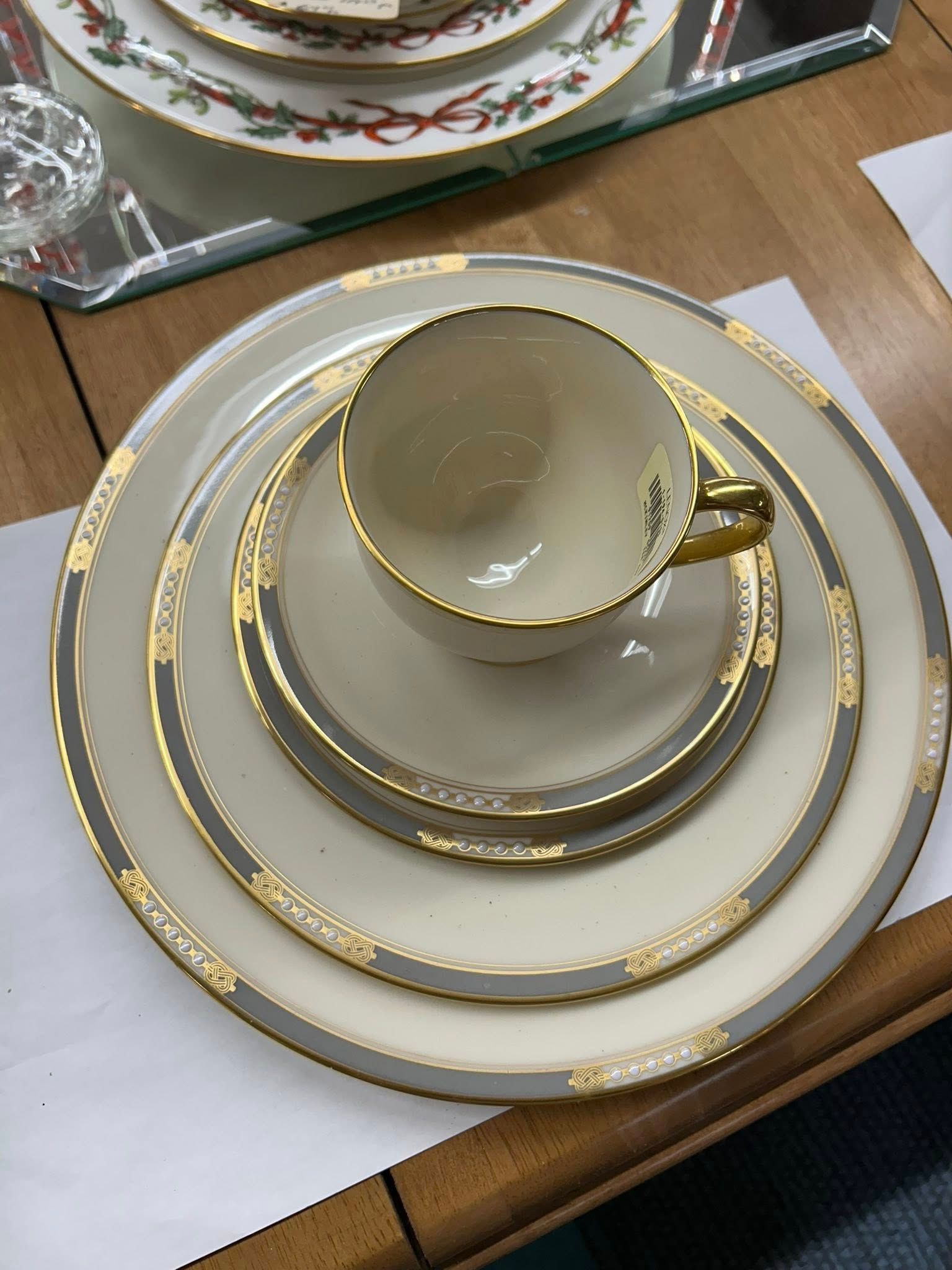 Gold-trimmed tea cup and saucer on stacked white-and-gold plates on a table.