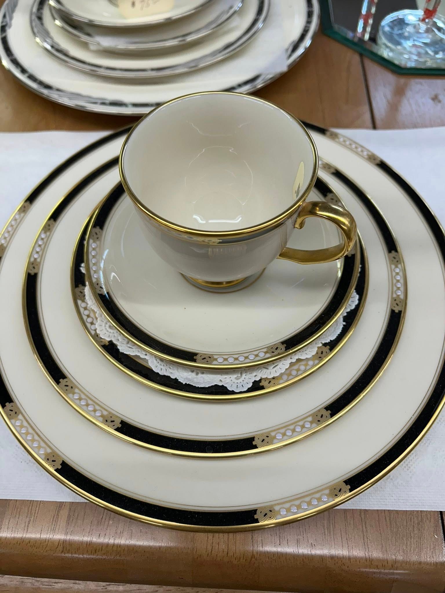 Elegant white-and-gold teacup set on stacked matching plates at a table setting