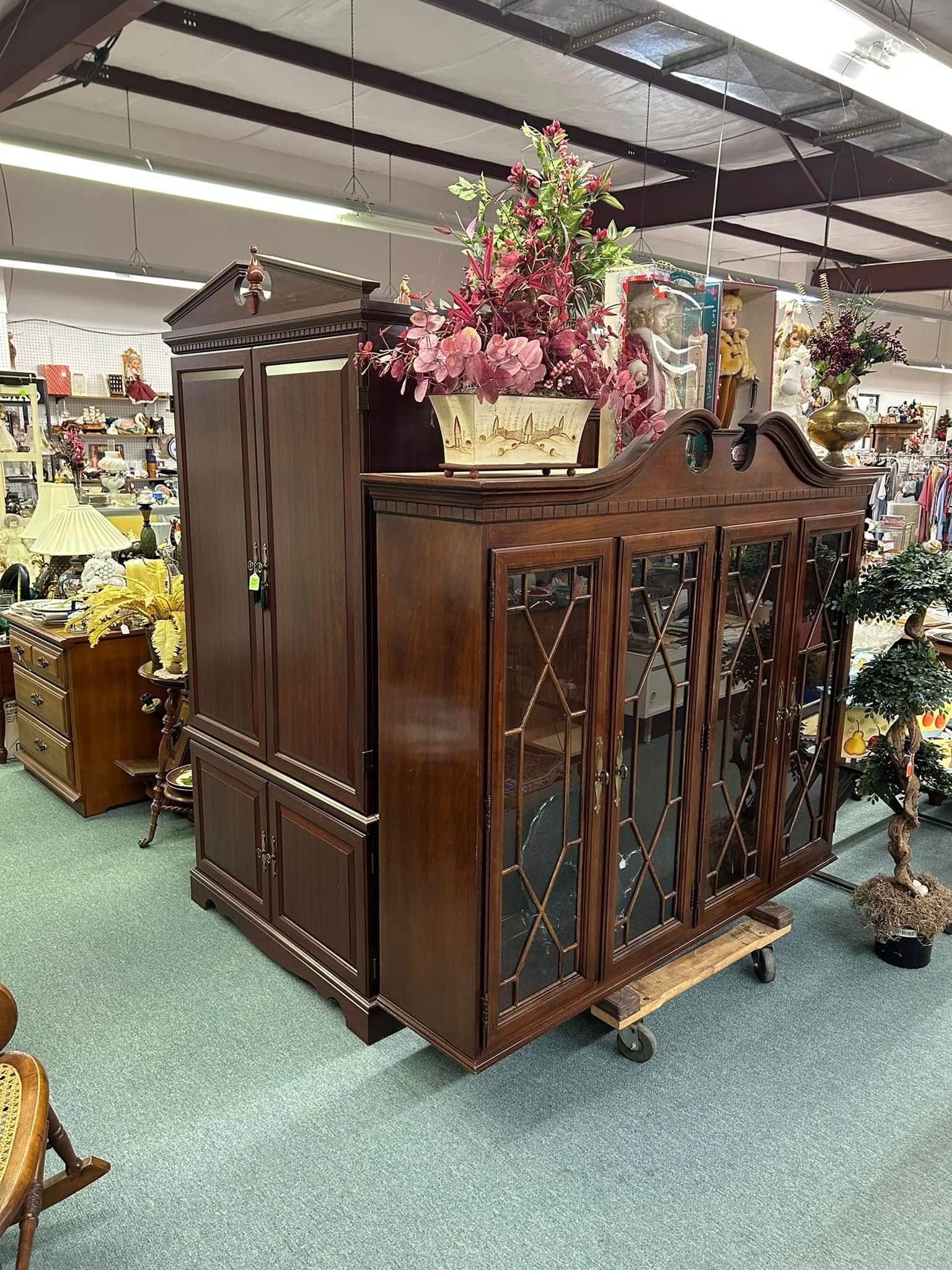Wooden shelf with assorted glass and ceramic decorative items, including blue and clear vases and cups.