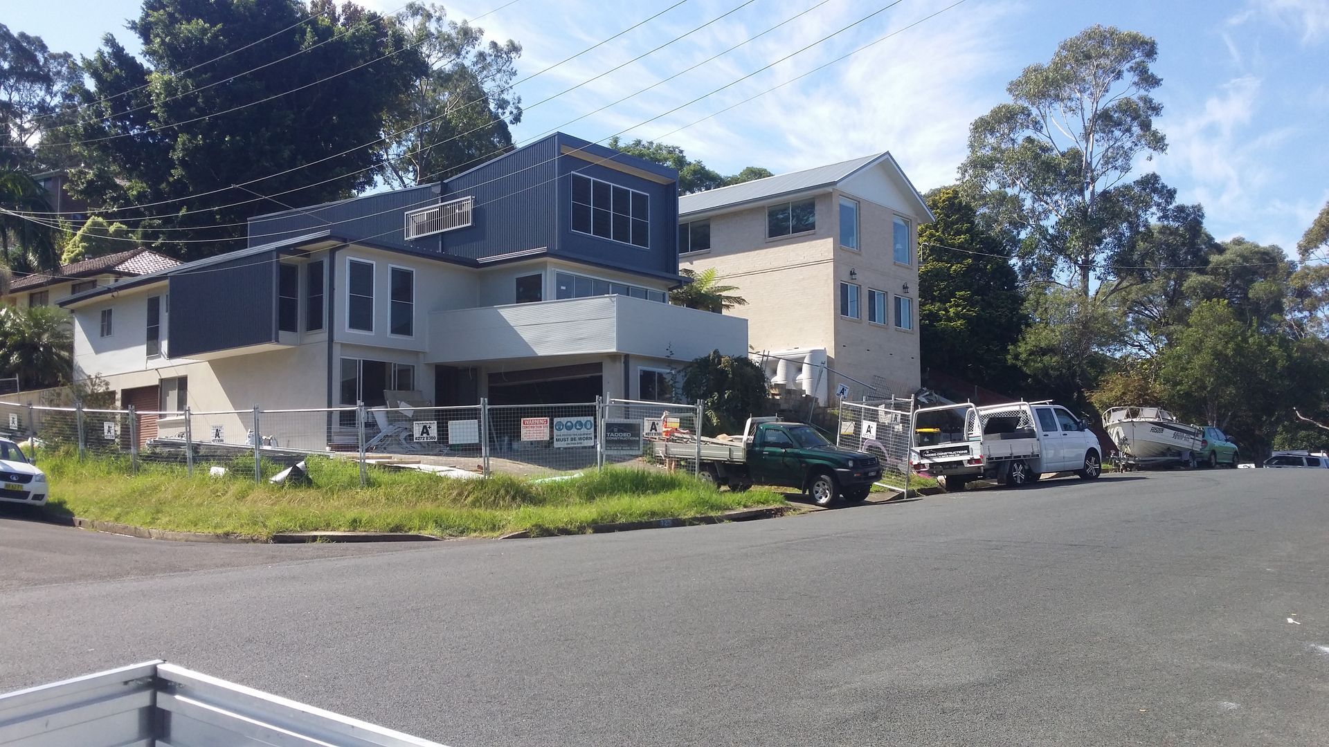 Two-story building on a sunny street corner with parked cars, trees, and blue sky