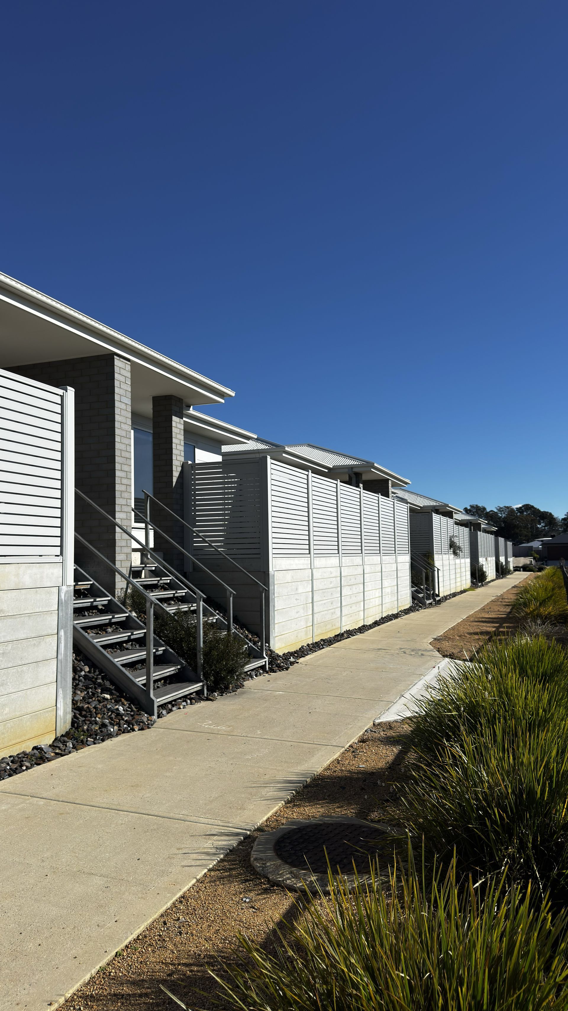 Apartment walkway beside white buildings under a clear blue sky