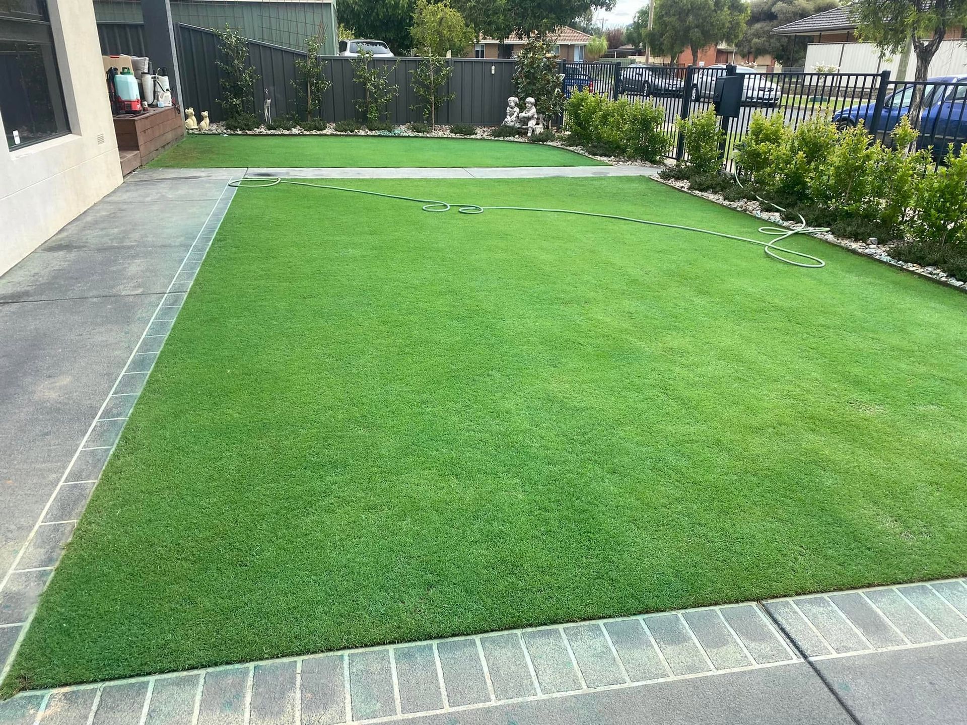 Neatly trimmed green lawn bordered by paving stones and shrubs in a residential yard