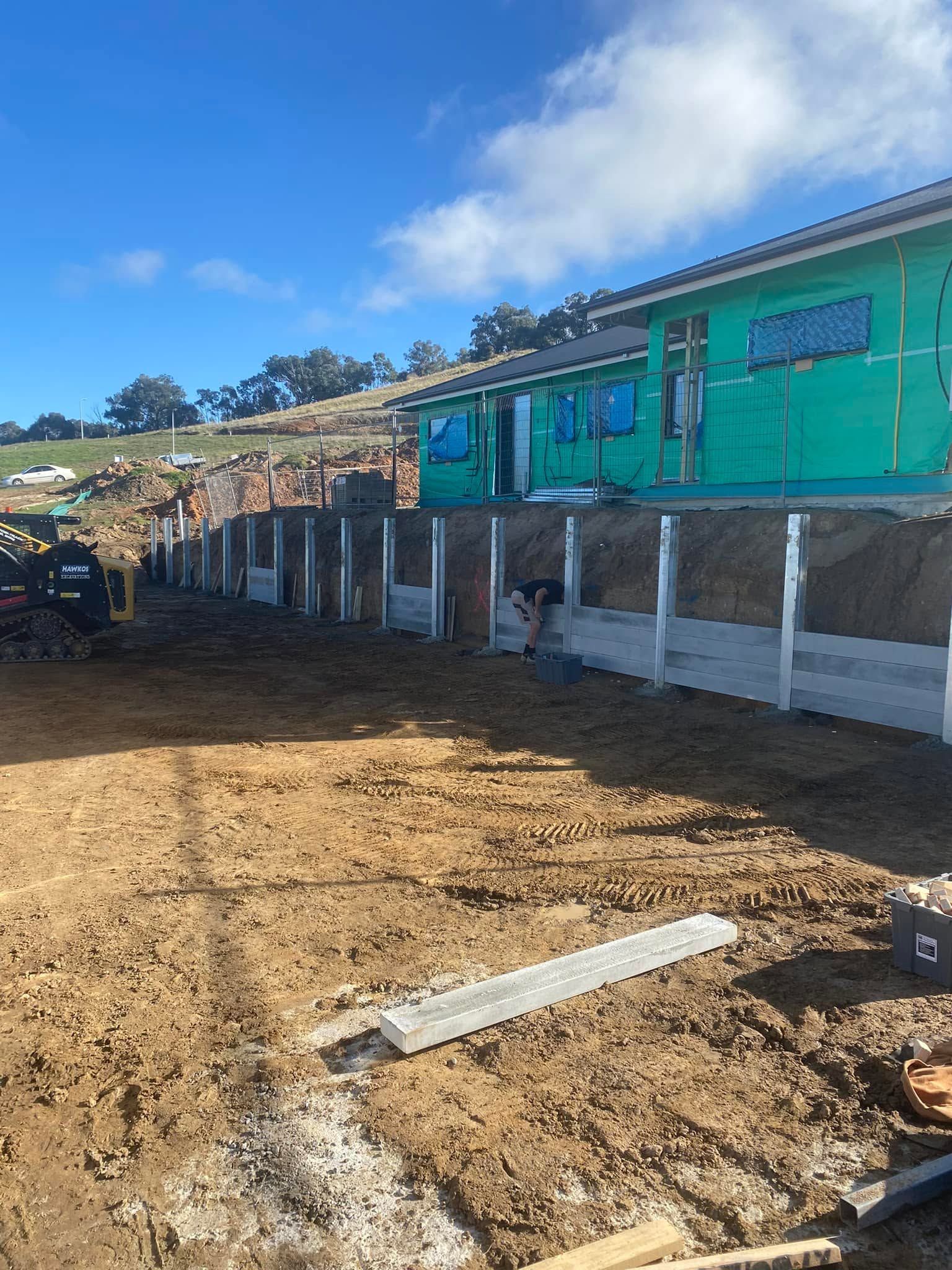 Rural building with green walls on stilts beside a dirt lot under a blue sky