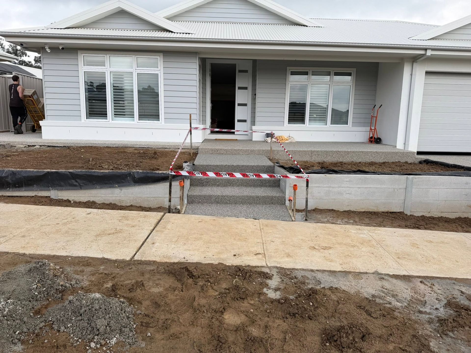 Newly built white house with unfinished front walkway and ramp under construction