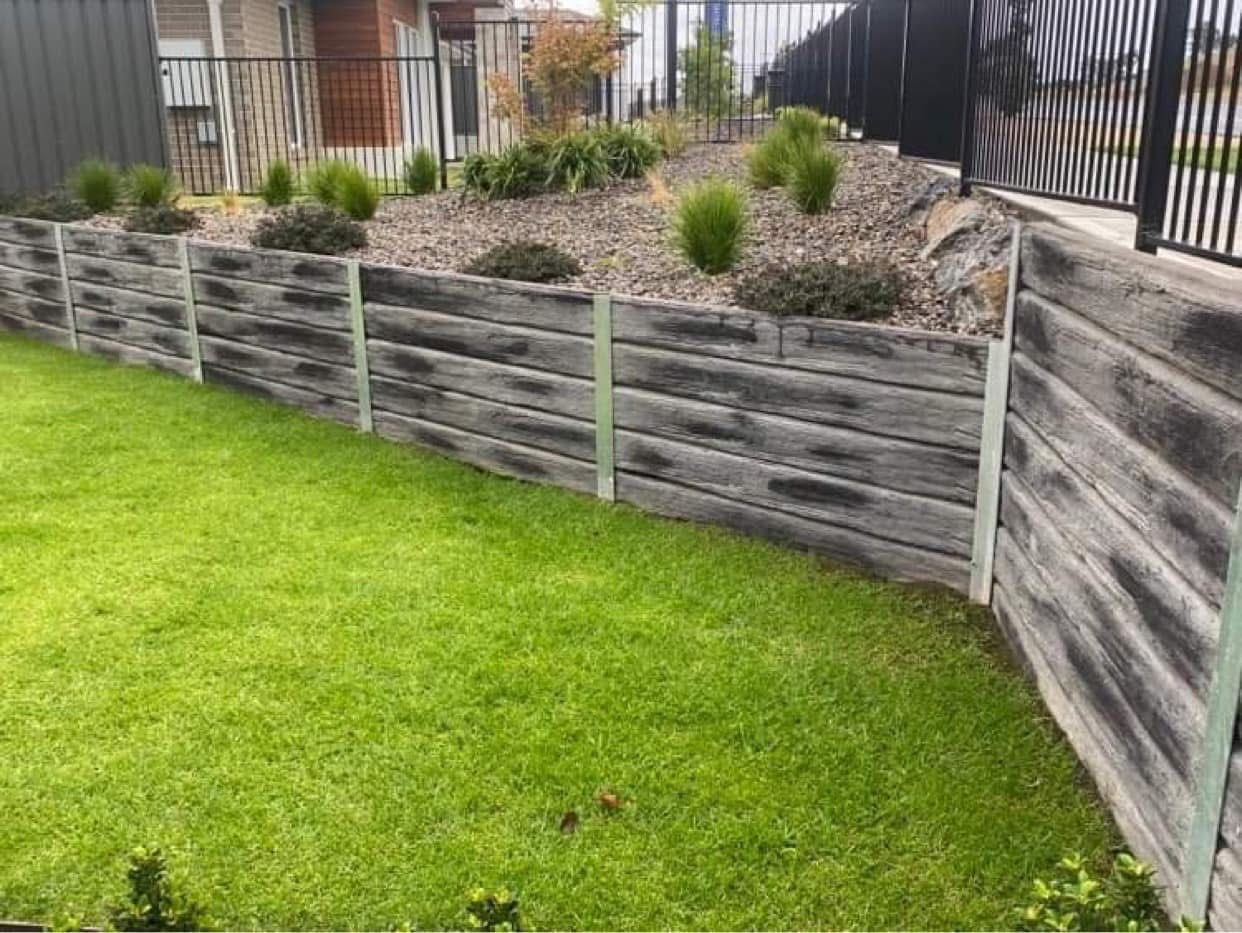 Terraced garden with green lawn, gray retaining walls, and shrubs on a sloped hillside