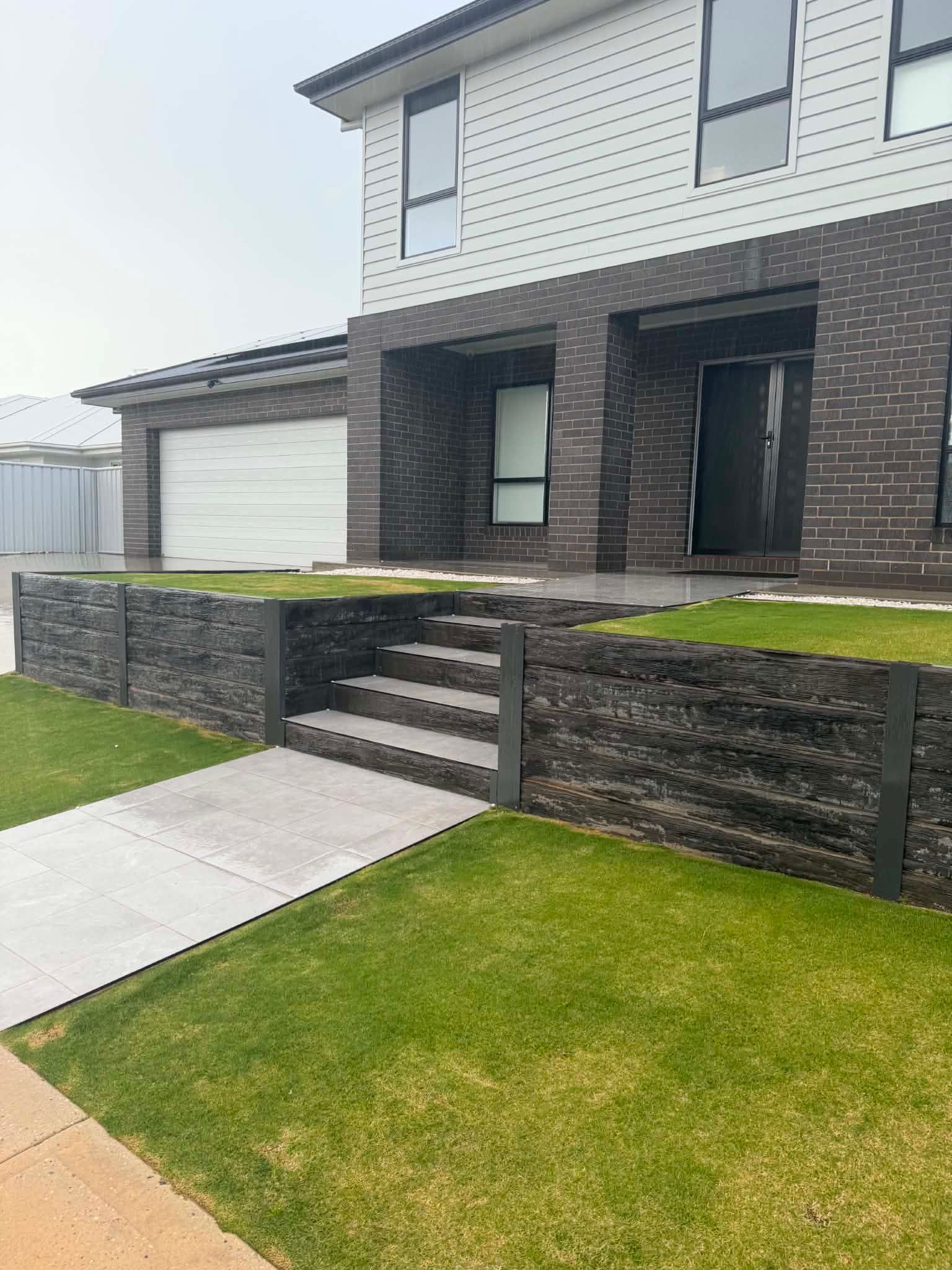 Modern two-story house with brick facade, front steps, garage, and neatly kept lawn