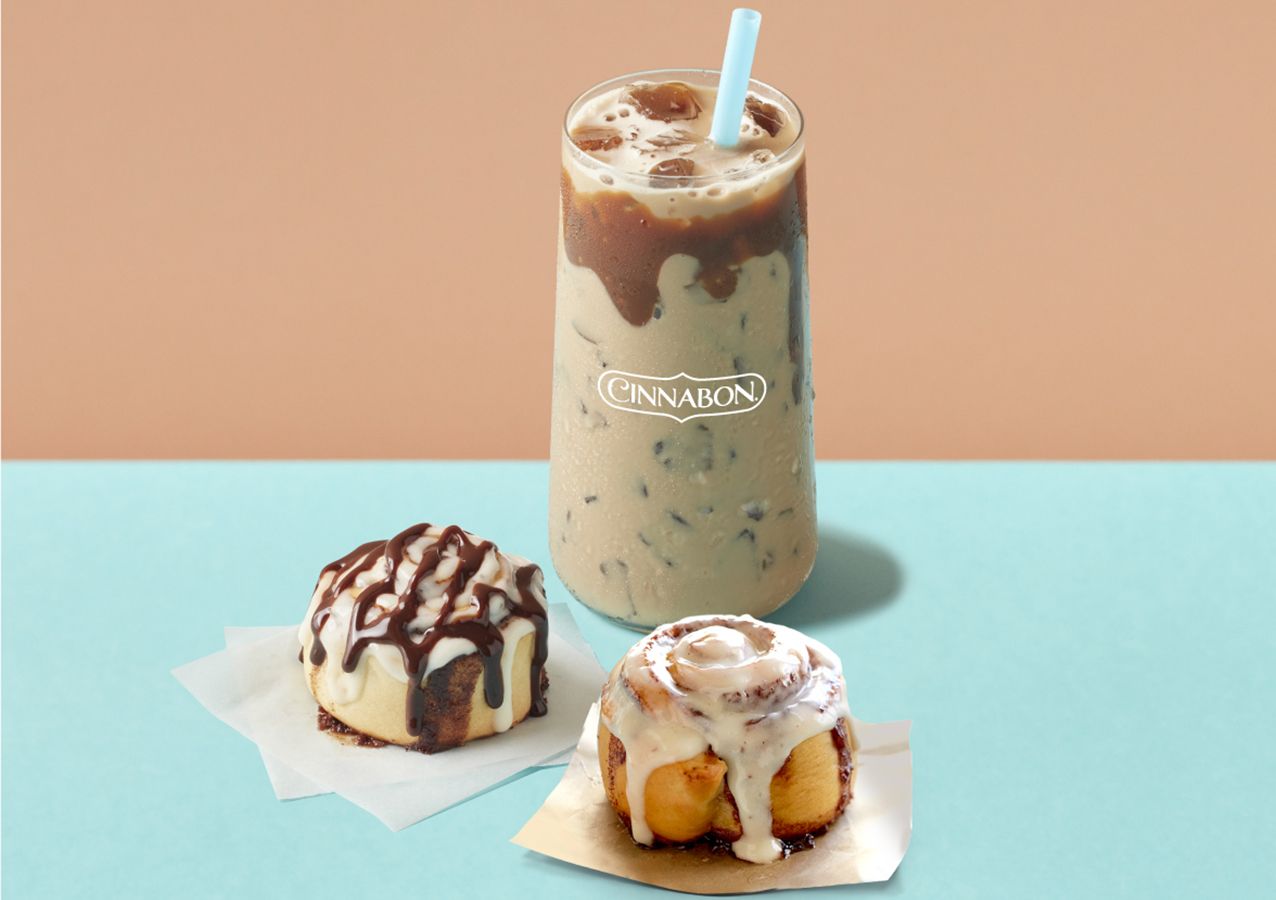 There are three cinnamon rolls and a milkshake on the table.