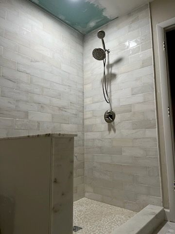 A bathroom with a walk in shower and two shower heads.
