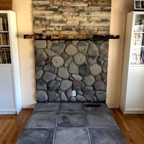 A living room with a stone fireplace and a tiled floor.