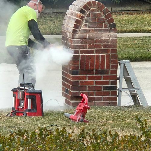 A man is spraying smoke on a brick chimney.